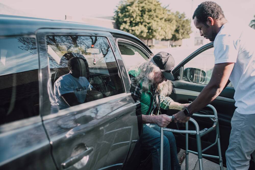 young man helping elderly out of the car young man helping elderly out of the car